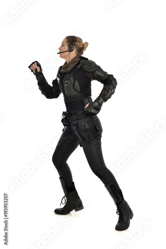 full length portrait of female soldier wearing black tactical armour, isolated on white studio background.