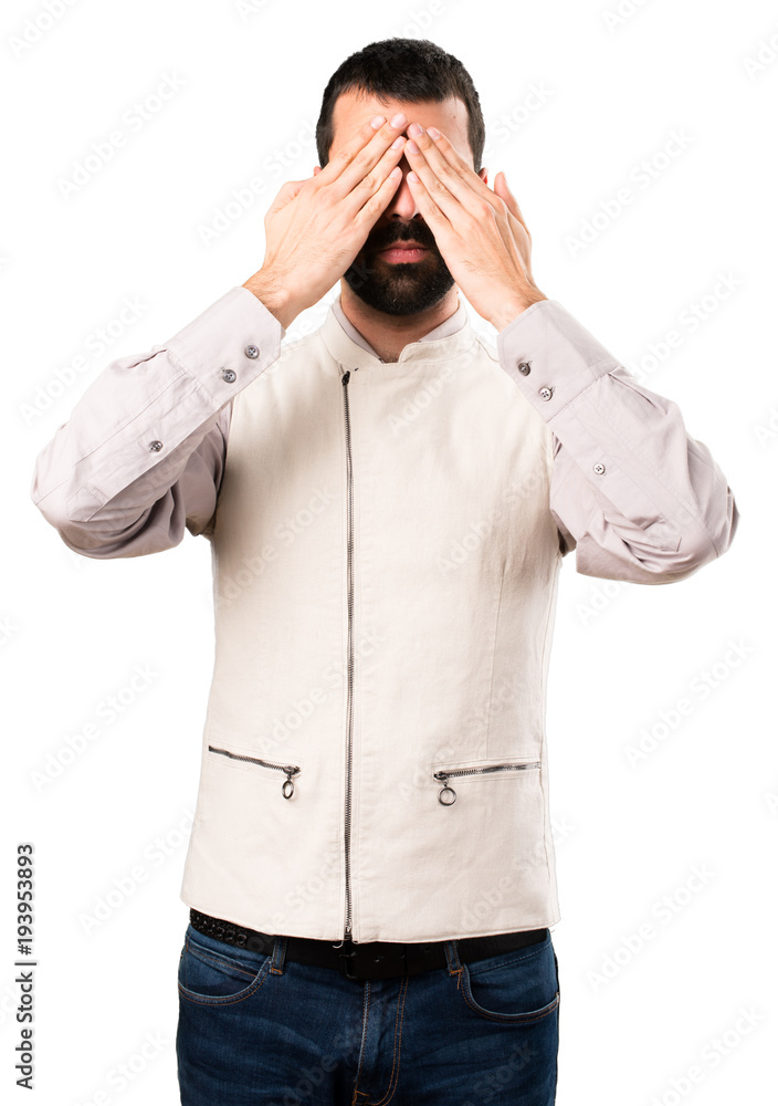 Handsome man with vest covering his eyes on isolated white background Handsome man with vest covering his eyes on isolated white background