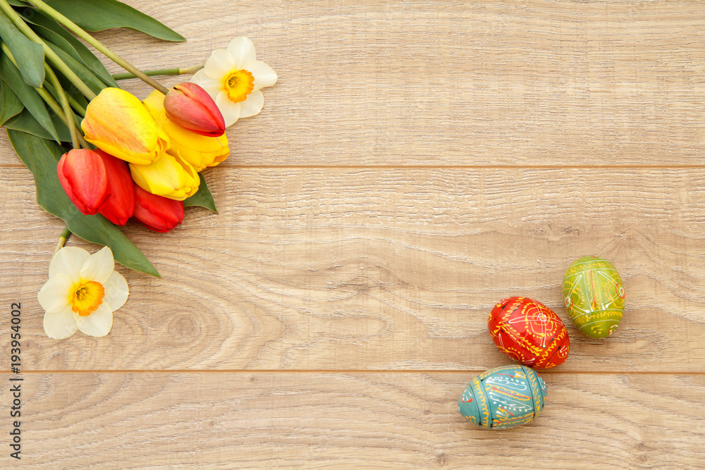 Painted Easter eggs, tulips and narcissus on wooden boards Painted Easter eggs, tulips and narcissus on wooden boards