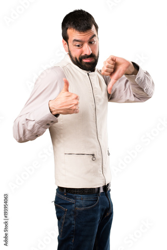 Handsome man with vest making good-bad sign on isolated white background
