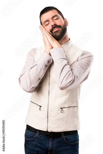 Handsome man with vest making sleep gesture on isolated white background