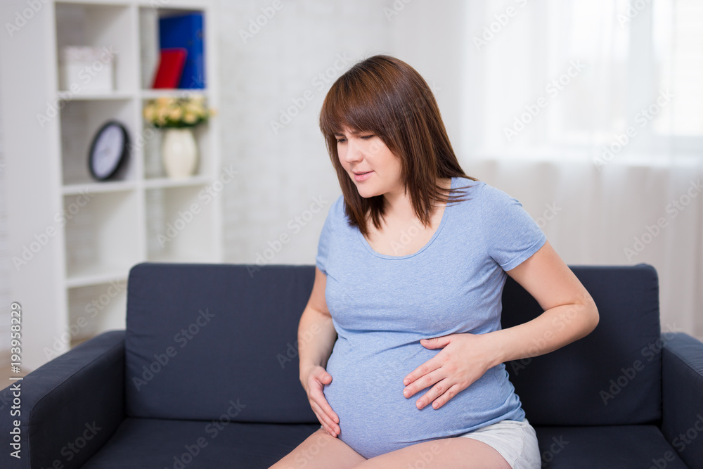 pregnant woman getting a contraction at home in the living room pregnant woman getting a contraction at home in the living room
