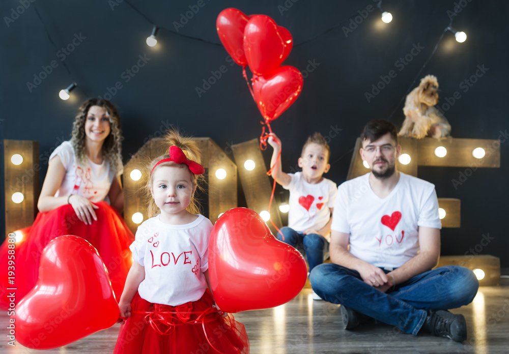 Beautiful young family and their little kids pose with balloons in a cosy studio.