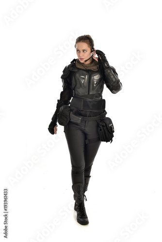 full length portrait of female soldier wearing black tactical armour, isolated on white studio background.