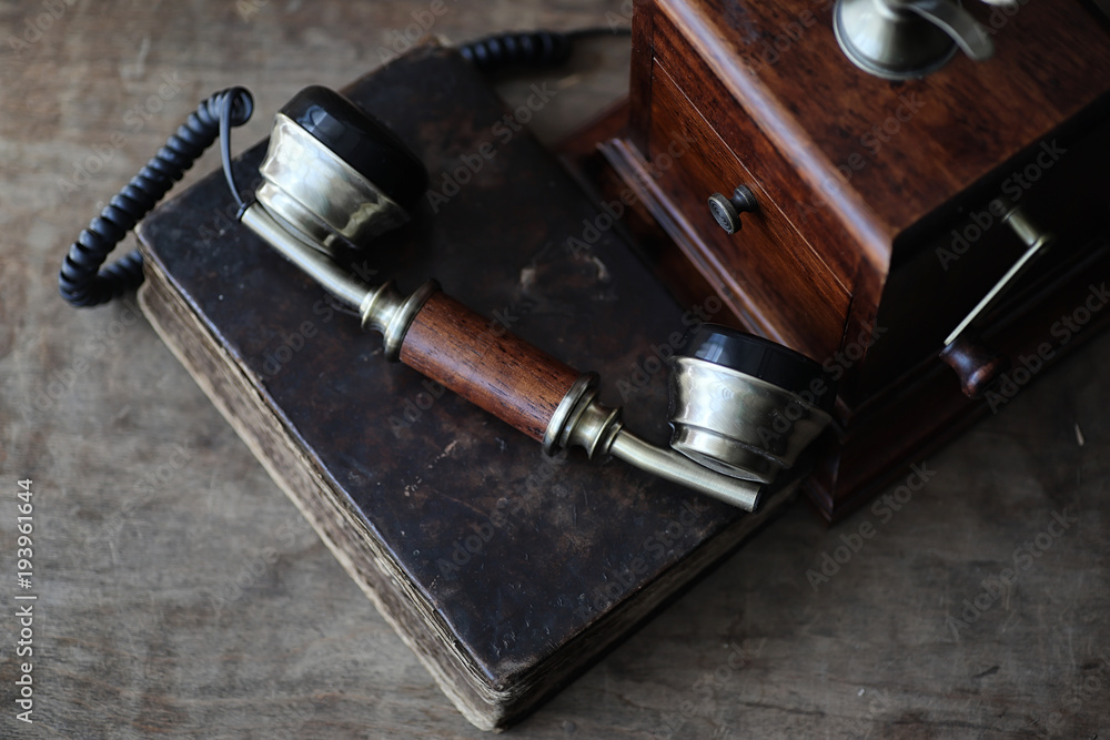 Old telephone and retro book on a wood