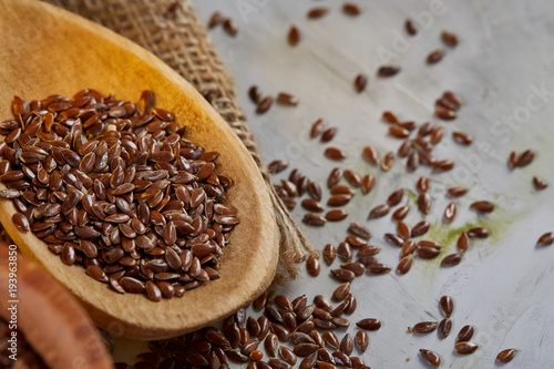 Flax seeds in bowl and flaxseed oil in glass bottle on wooden background, top view, close-up, selective focus © Aleksey