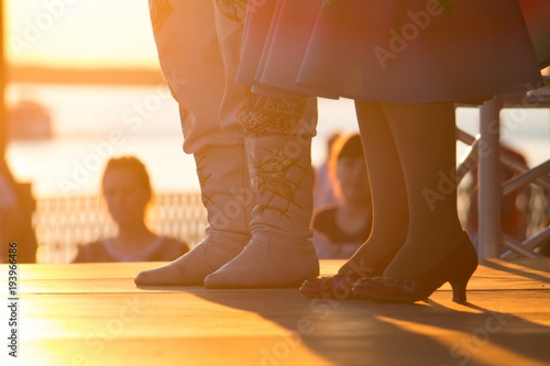 dancers' feet in shoes while dancing at a festival during the orange sunset