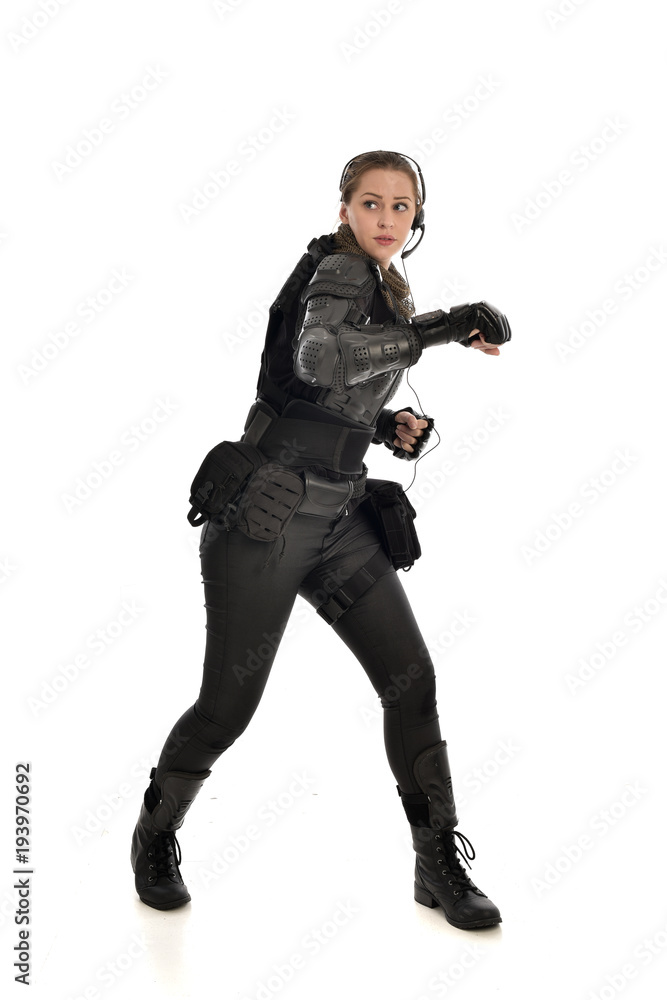 full length portrait of female  soldier wearing black  tactical armour, isolated on white studio background.