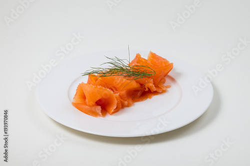 Slices of folded Salmon on a white plate on a white background