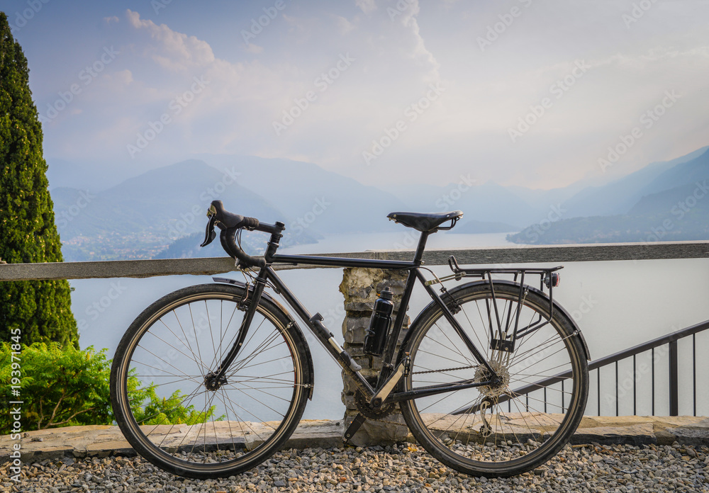 Touring bicycle next to railing with the beautiful view of Lake Como, Lombardy, Italy towards Bellagio