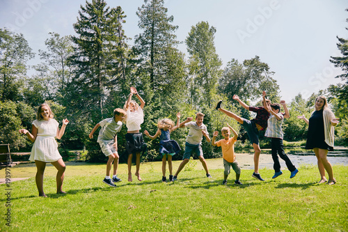 Happy children jumping or dancing in summer park
