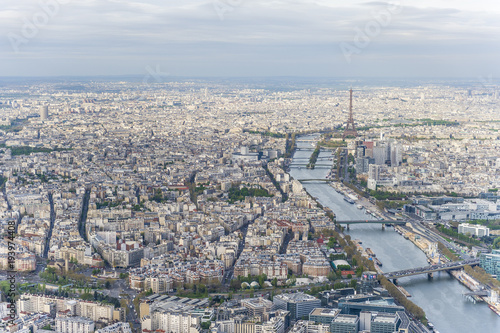 Aerial view of Paris city center with the Seine river and its bridges in the foreground and the Eiffel tower in the background.