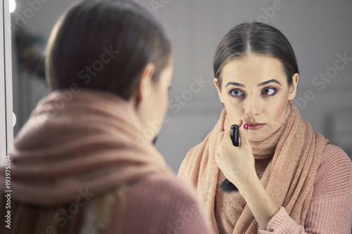 beautiful girl doing make-up near a mirror