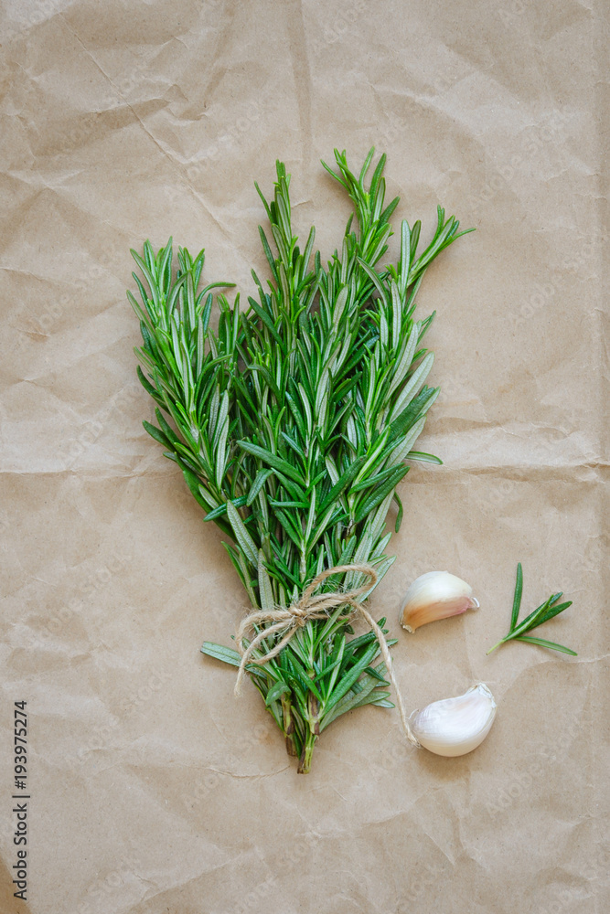 Bunch of rosemary with garlic on wrapping paper Bunch of rosemary with garlic on wrapping paper