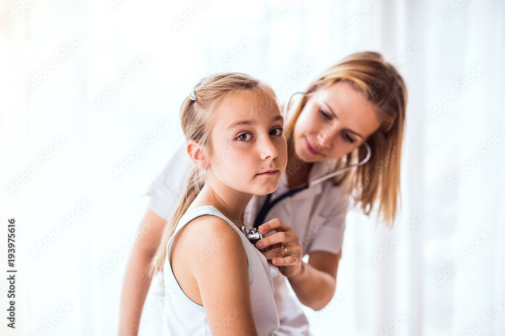 Young female doctor examining a small girl in her office.