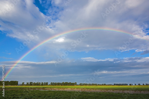 Bright rainbow in the high sky over the flood meadows of Normandy in spring day, France © Arkadii Shandarov