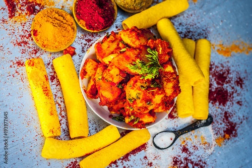 Indian appetizer dish i.e.Teekha Laal Batata or Spicy potato with  all its ingredients and spices on a sliver wooden surface.This dish is popularly eaten with crunchy fired sticks Bhongla. photo