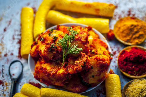 Indian appetizer dish i.e.Teekha Laal Batata or Spicy potato with  all its ingredients and spices on a sliver wooden surface.This dish is popularly eaten with crunchy fired sticks Bhongla. photo