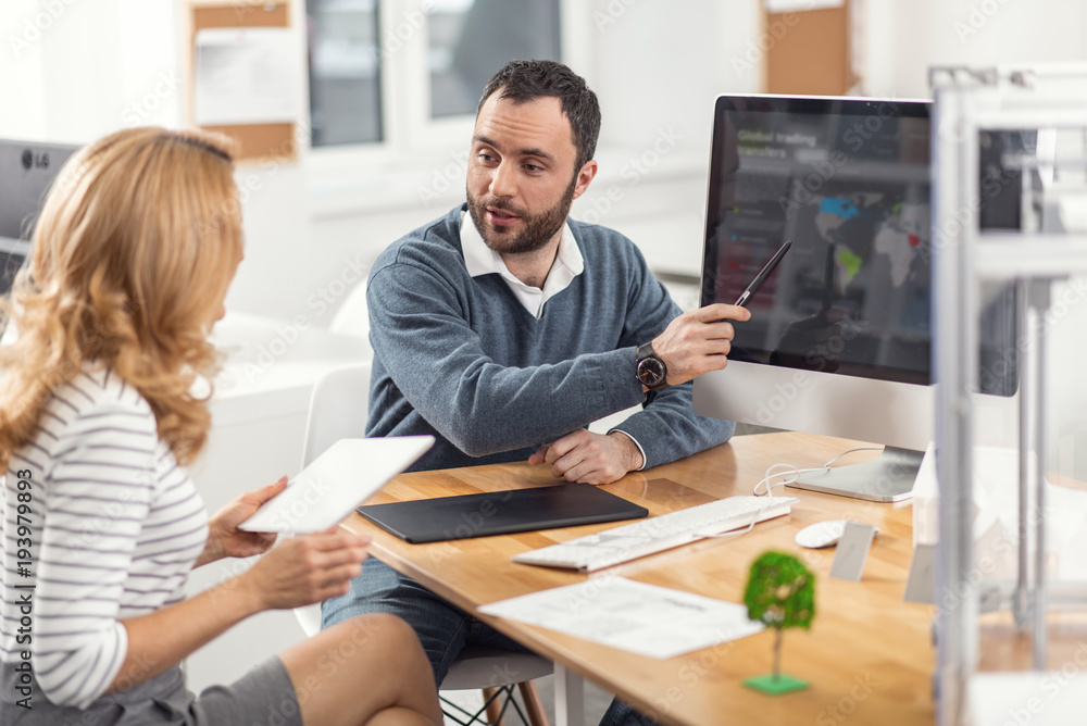 Perfect presentation. Lively young man pointing at the computer screen and presenting his project to his female boss while the woman listening to him attentively Perfect presentation. Lively young man pointing at the computer screen and presenting his project to his female boss while the woman listening to him attentively