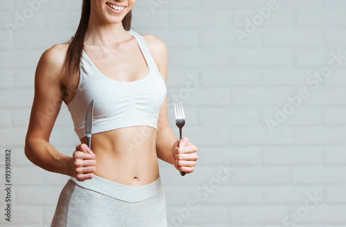 Beautiful, fit young woman holding a fork and a knife 