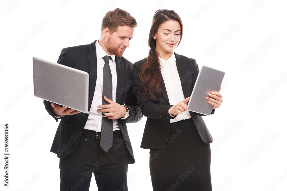 Studio portrait of Asian businesswoman and Caucasian businessman holding laptop and tablet computer Studio portrait of Asian businesswoman and Caucasian businessman holding laptop and tablet computer