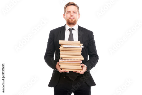 Portrait of young manager holding stack of books