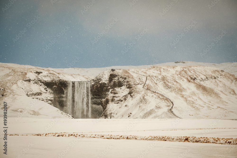 Fototapeta premium Skogafoss, the great and beautiful waterfall in Iceland during winter. Snow blizzard in Iceland near famous Skogafoss waterfall.