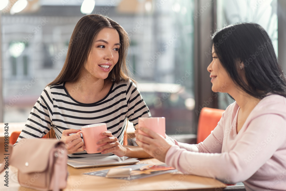 Pleasant communication. Nice positive delighted women having tea and talking to each other while meeting in the cafe Pleasant communication. Nice positive delighted women having tea and talking to each other while meeting in the cafe