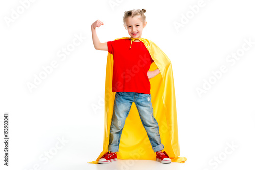 Canvas Print Smiling supergirl in yellow cape showing muscles on hand isolated on white