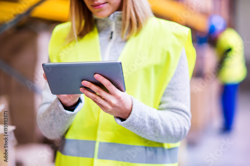 Unrecognizable woman warehouse worker with tablet.