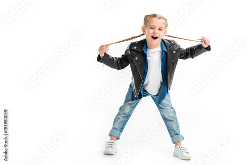 Excited child in black leather jacket holding her pigtails isolated on white © LIGHTFIELD STUDIOS