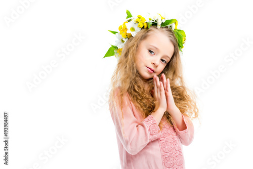 Little child holding handbreadths together and wearing wreath band from flowers isolated on white