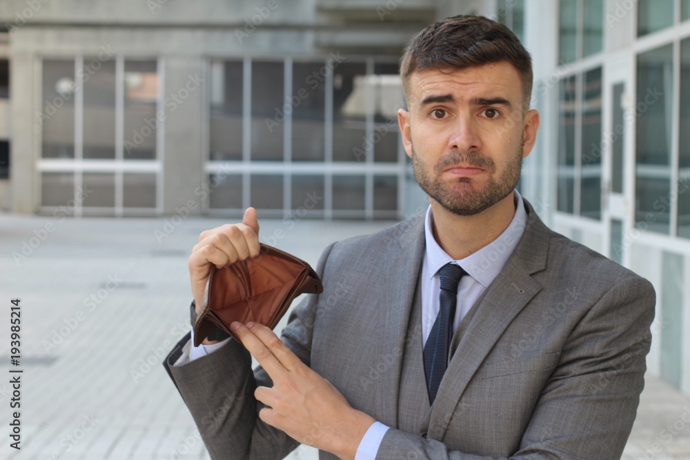 Fototapeta premium Perplexed businessman holding his empty wallet
