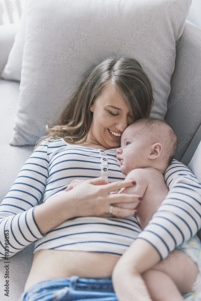 Young mother holding her newborn child. Woman and new born boy relax. Family at home. Portrait of happy mother and baby. Young beautiful mom lying at bed with a cute little child. Young mother holding her newborn child. Woman and new born boy relax. Family at home. Portrait of happy mother and baby. Young beautiful mom lying at bed with a cute little child.
