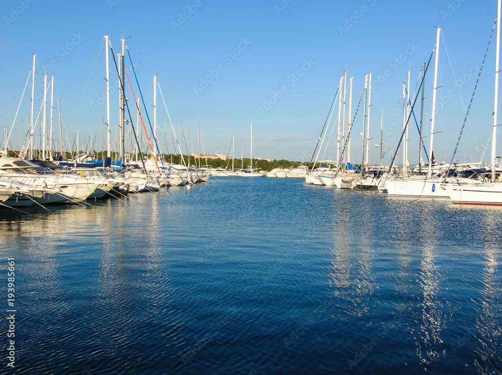 Boating Lifestyle. Boats docked in a marina with a rocky foreground and the beginning of a sunset in the background.