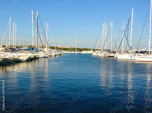 Boating Lifestyle. Boats docked in a marina with a rocky foreground and the beginning of a sunset in the background.