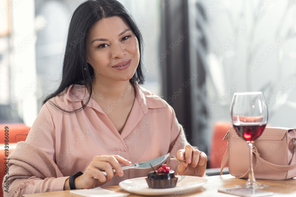 In the restaurant. Happy nice young woman looking at you and smiling while enjoying her meal In the restaurant. Happy nice young woman looking at you and smiling while enjoying her meal