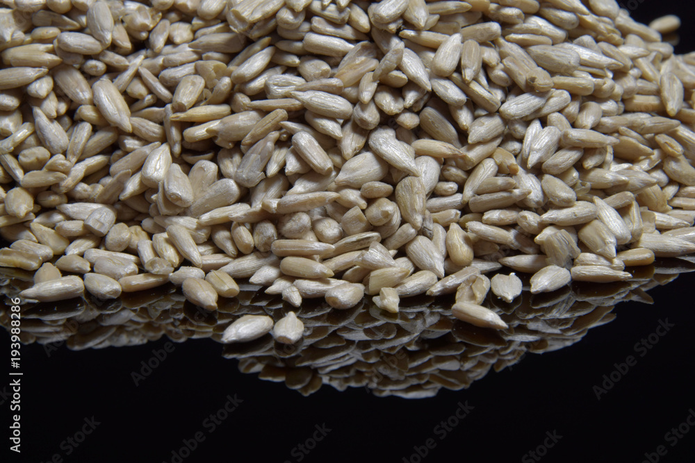 Obraz premium Sunflower peeled seeds on a black background.