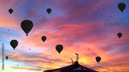 Black silhouettes of the hot air baloons over the circus tent on colorful sunset background