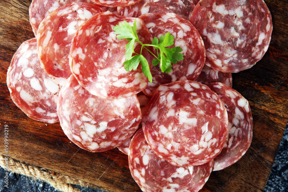 thinly sliced salami on a wooden texture on the background. thinly sliced salami on a wooden texture on the background.