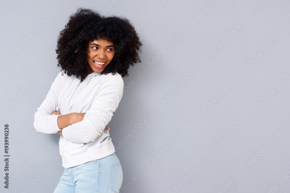 Attractive african woman standing with her arms crossed and smiling against gray background Attractive african woman standing with her arms crossed and smiling against gray background