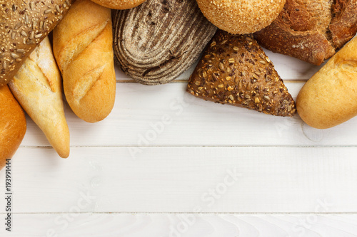 Assortment of baked bread on white wooden table background. top view with copy space
