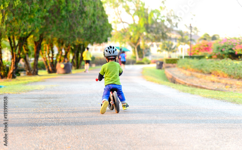 young boy riding bikes in the garden with soft-focus and over light in the background