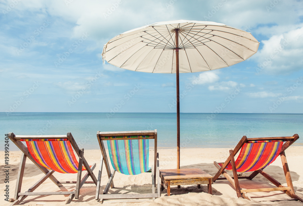 beach lounge chairs under umbrella on beach. Stock Photo Adobe Stock