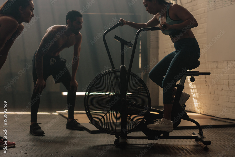 Fitness woman doing spinning at gym with trainers Fitness woman doing spinning at gym with trainers