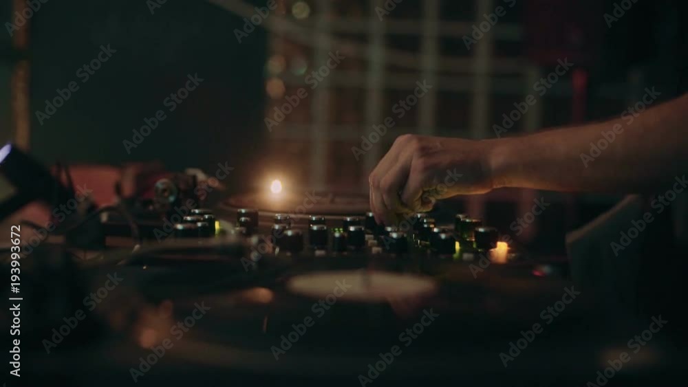 Side view of dj on mixing table or in recording studion, play records or record sound track, remixes song and creates music beat at party or contemporary music concert Side view of dj on mixing table or in recording studion, play records or record sound track, remixes song and creates music beat at party or contemporary music concert