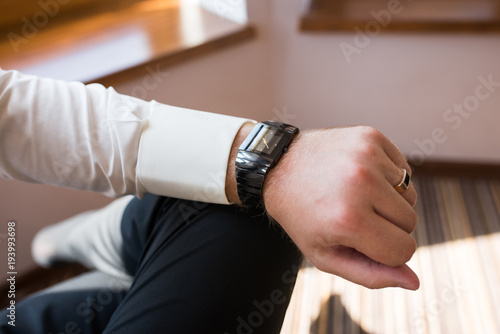 Man looking at his stylish watch on the left hand with a ring on the finger. Watch