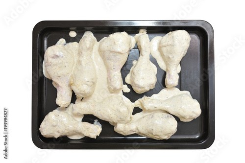 Cooking chicken legs. Chicken meat is laid on a baking sheet for baking in the oven. Isolated