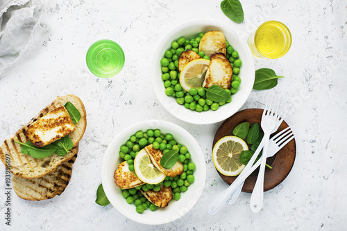 Green young peas, cheese haloumi, lemon. orange salad with slices of bread. Top View