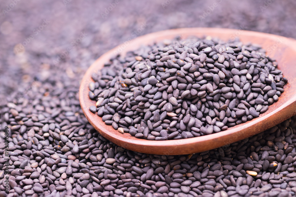 Black sesame in wooden spoon on sesame background. Black sesame in wooden spoon on sesame background.